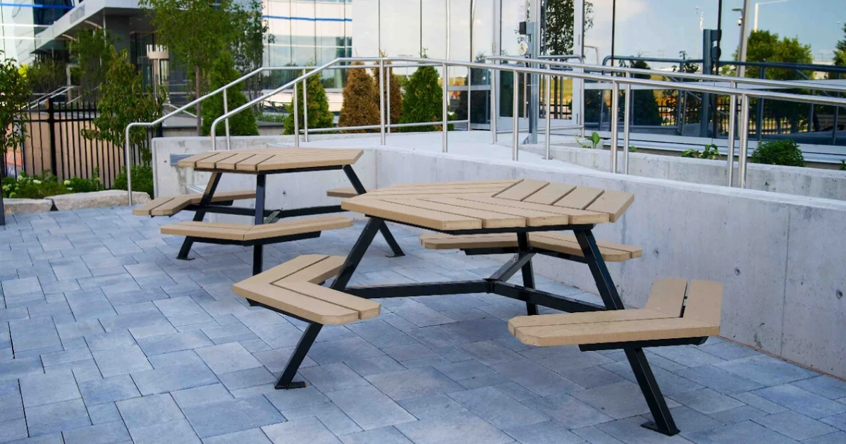 Modern hexagon-shaped picnic tables on a paved patio outside a commercial building